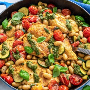 One-pan pesto chicken with vegetables and butter beans in a skillet.