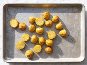 STEP 1 Seasoned potato chunks spread on a sheet pan after roasting.