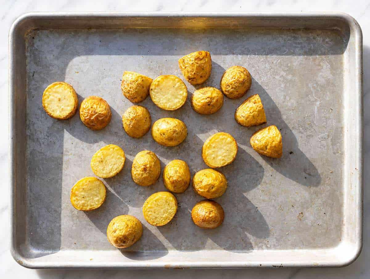 STEP 1 Seasoned potato chunks spread on a sheet pan after roasting.