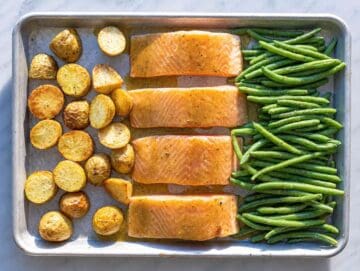 STEP 3 Salmon fillets and green beans arranged next to partially roasted potatoes.