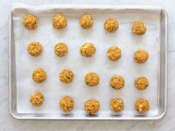 Step 2 Raw Greek turkey meatballs shaped on parchment-lined sheet pan before baking