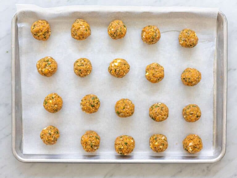 Step 2 Raw Greek turkey meatballs shaped on parchment-lined sheet pan before baking