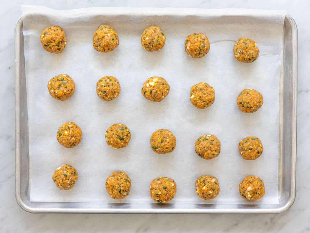 Step 2 Raw Greek turkey meatballs shaped on parchment-lined sheet pan before baking