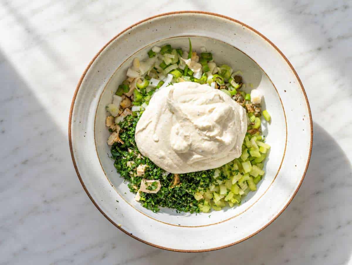 Step 2 Shredded chicken, celery, herbs, and pickles mixed with creamy dressing in large bowl.