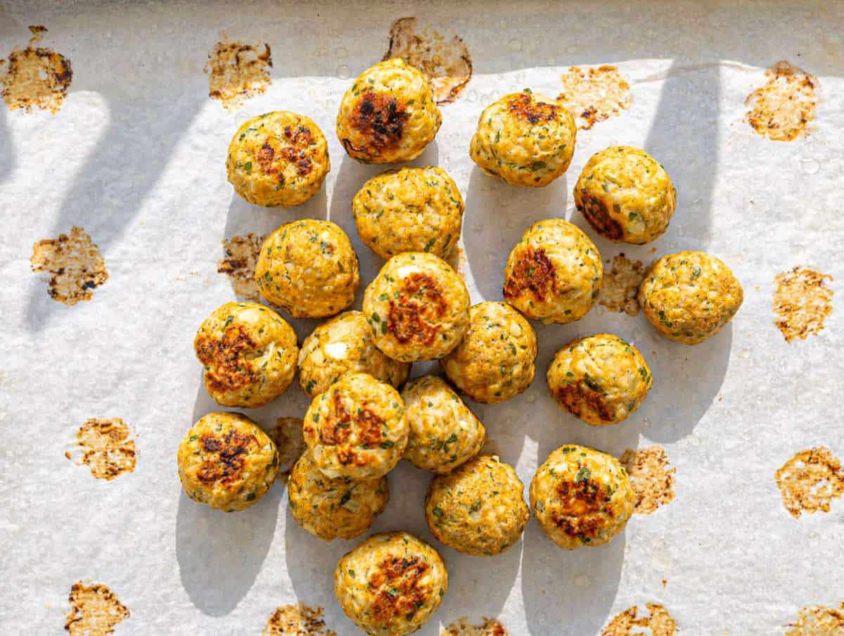 Step 3 Baked Greek turkey meatballs golden on top with herbs and feta on sheet pan.