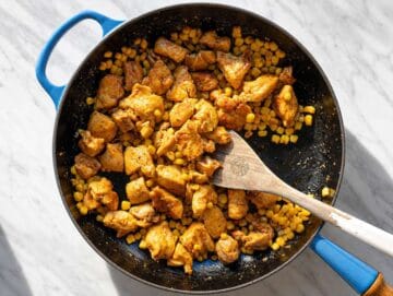 Step 3 Seasoned chicken cooking with corn in skillet until lightly charred and golden.