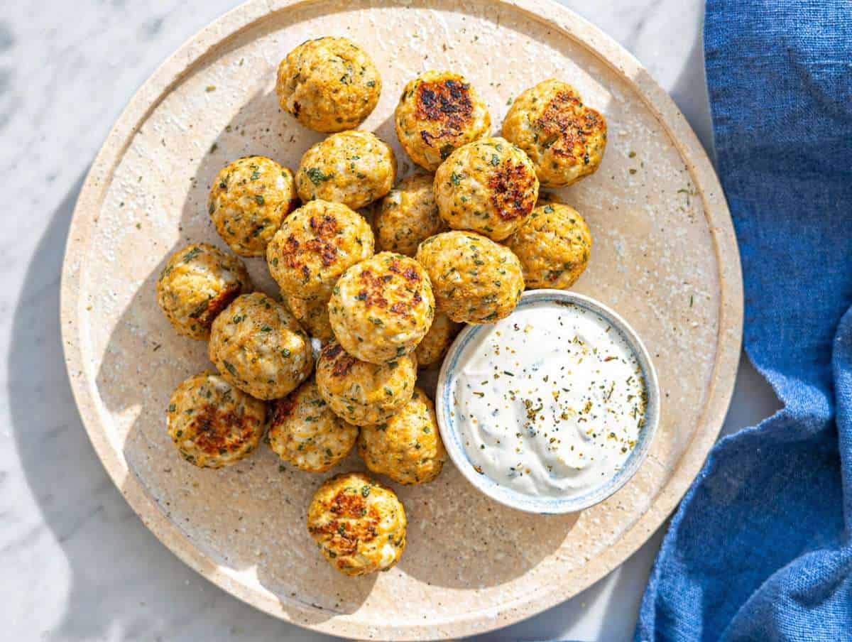 Step 4 Greek turkey meatballs served with creamy tzatziki on ceramic plate in natural light.