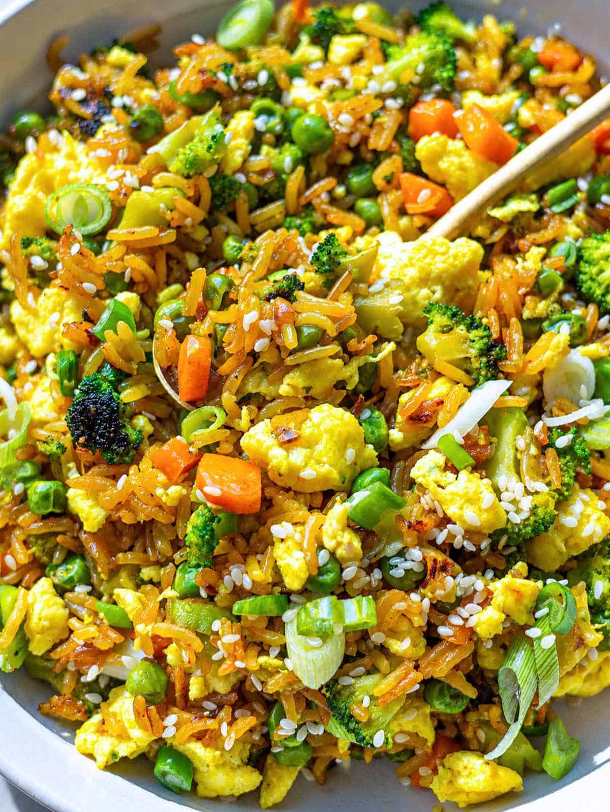 Close-up of egg fried rice with cottage cheese and tender shiny vegetables.