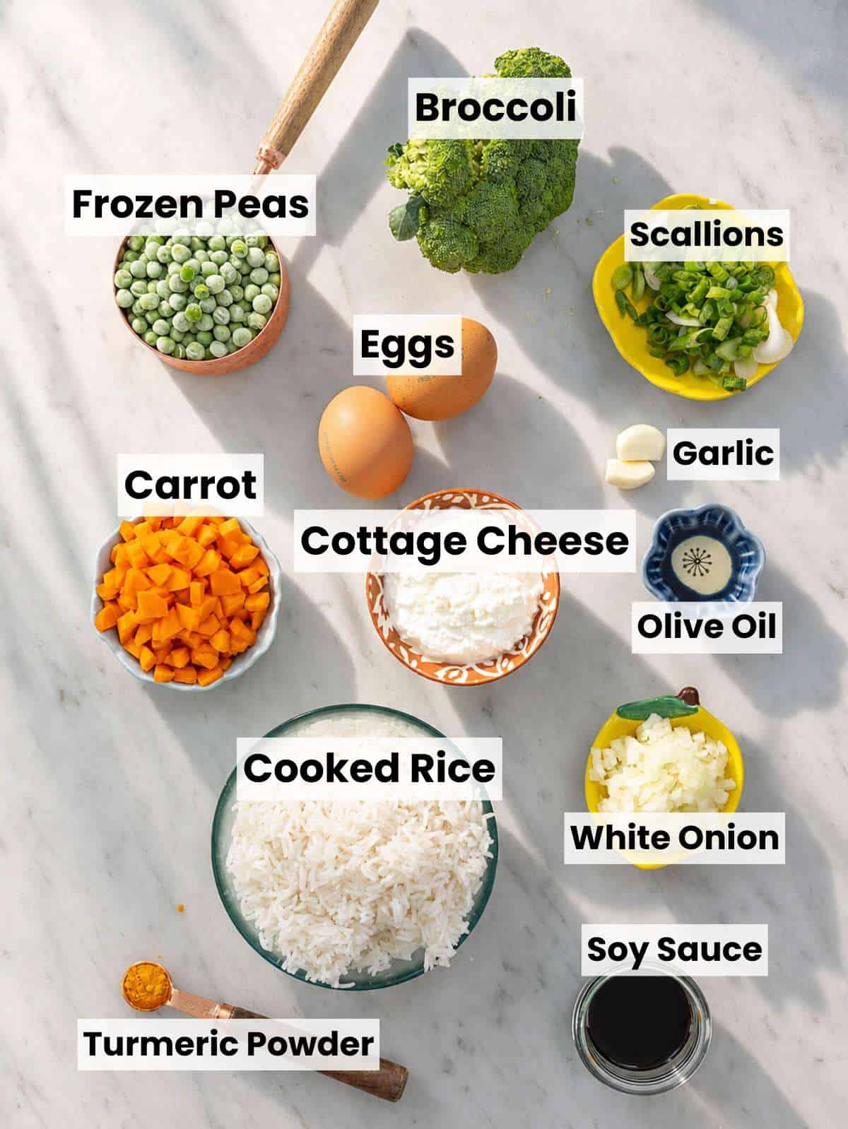 Ingredients for egg fried rice with cottage cheese arranged on a marble countertop.