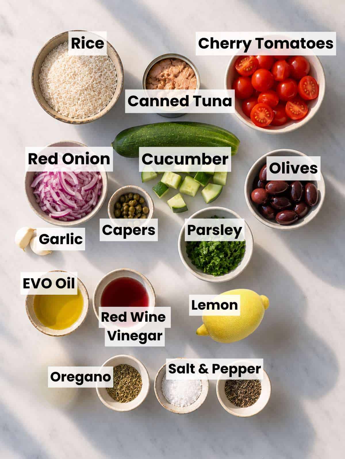 Rice, tuna, vegetables, and dressing ingredients arranged on a marble kitchen counter