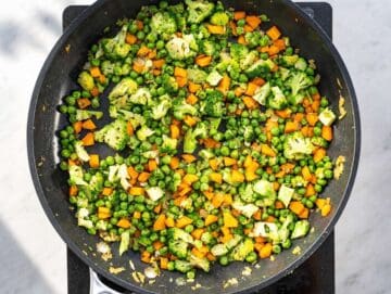 Step 2 Chopped onion, carrot, and broccoli sautéing in a hot skillet.